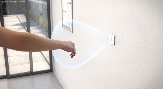 Hand betätigt einen berührungslosen Schalter, der die automatische Tür öffnet.