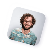 Mann mit gelockten, dunklen Haaren und Brille, schaut freundlich in die Kamera.