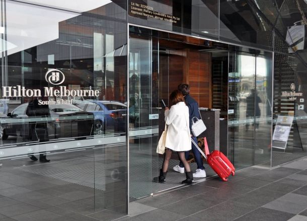 Zwei Personen betreten durch die Schiebetür das Hilton Hotel.