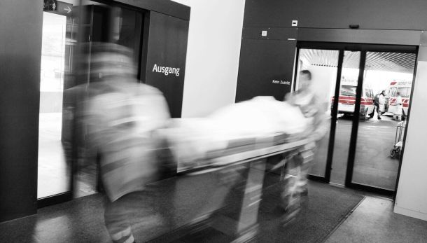 Person wird schnell von zwei Rettungswagenfahrern auf einem Krankenbett transportiert.