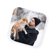 Sympathischer Mann mit einem Hund auf dem Arm.